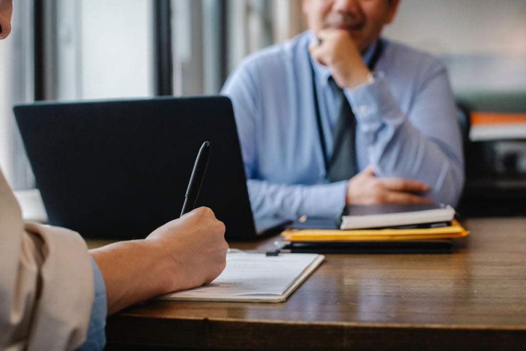 a person writing on a notepad across a doctor in a blue button up shirt
