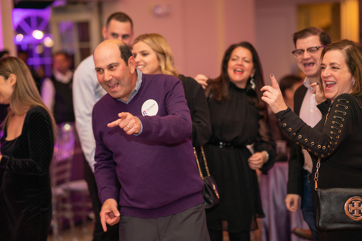a man in a purple shirt dancing at the Progress Forward Gala